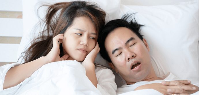 Young couple in bed, one is frustrated at the other for snoring
