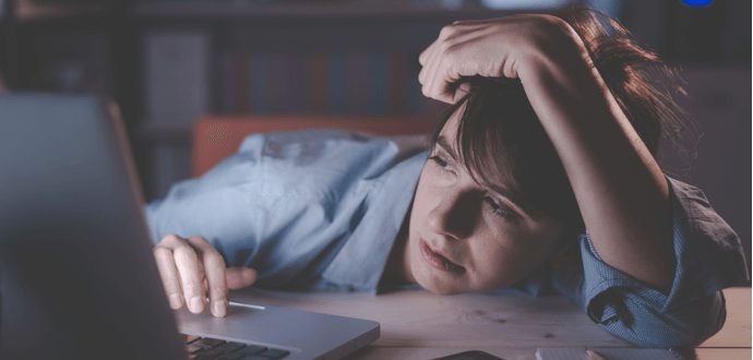 Exhausted woman suffering from sleep deprivation on laptop late at night